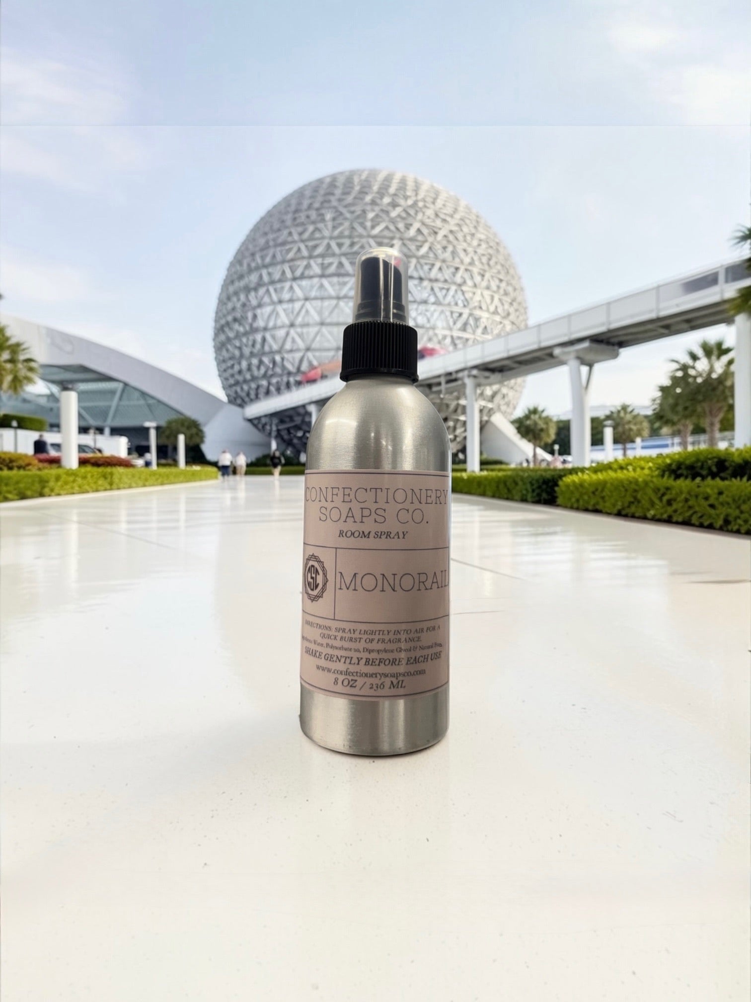 Bottle of Confectionaire Soaps Co. room spray with a futuristic building in the background