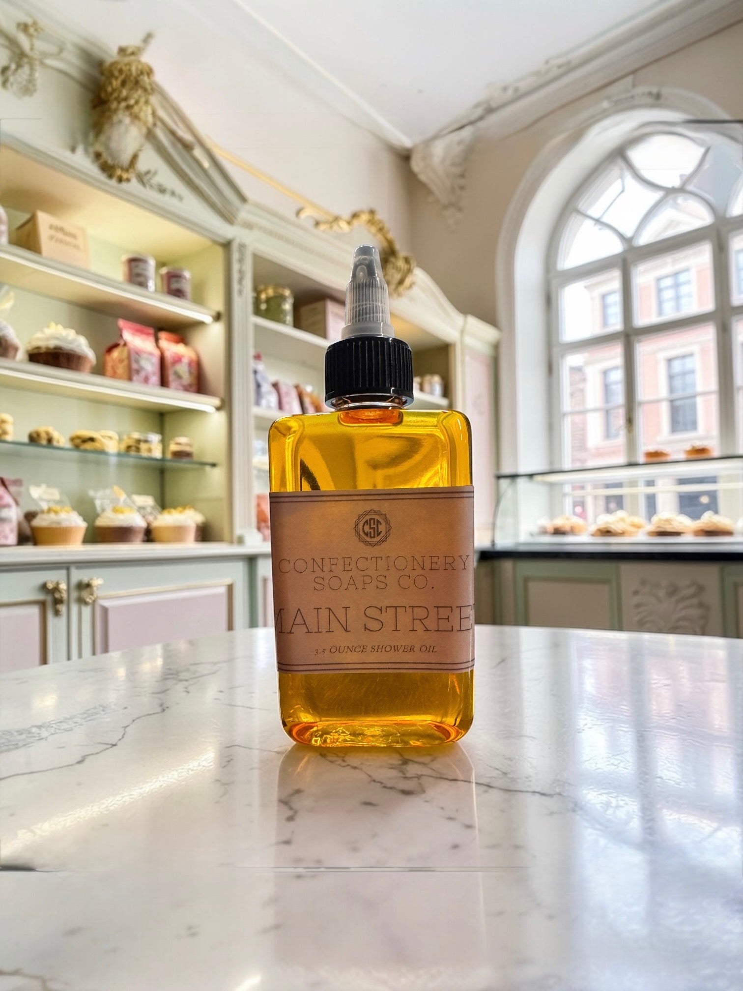 Bottle of Confectionery Soaps Co. Rain Street soap on a marble surface with a bakery in the background.