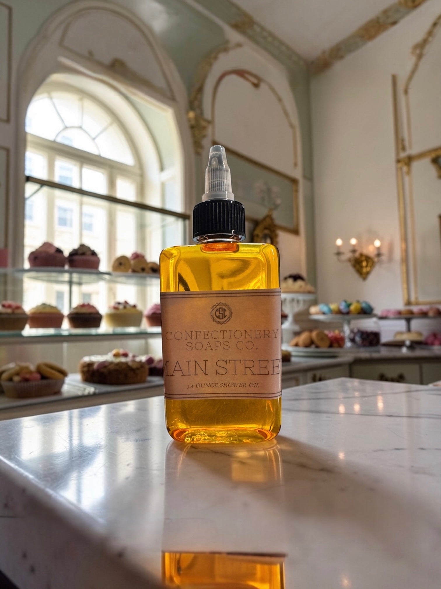 Bottle of Confectionery Soaps Co. soap on a marble counter with a bakery in the background