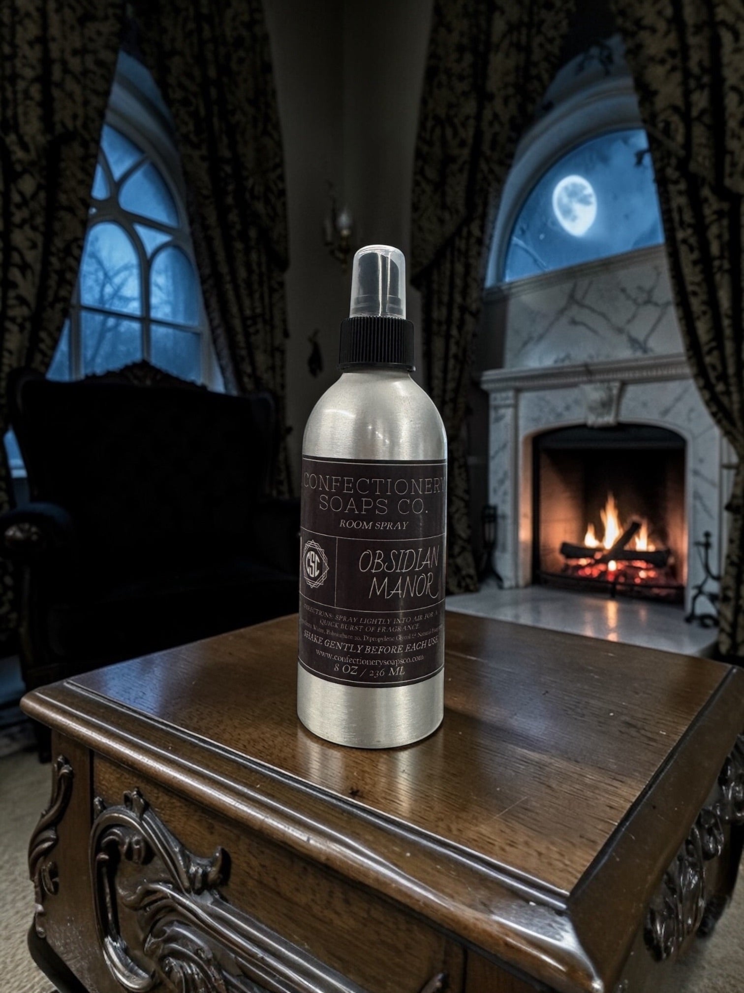 Bottle of Obsidian Manor room spray on a wooden table with a fireplace in the background
