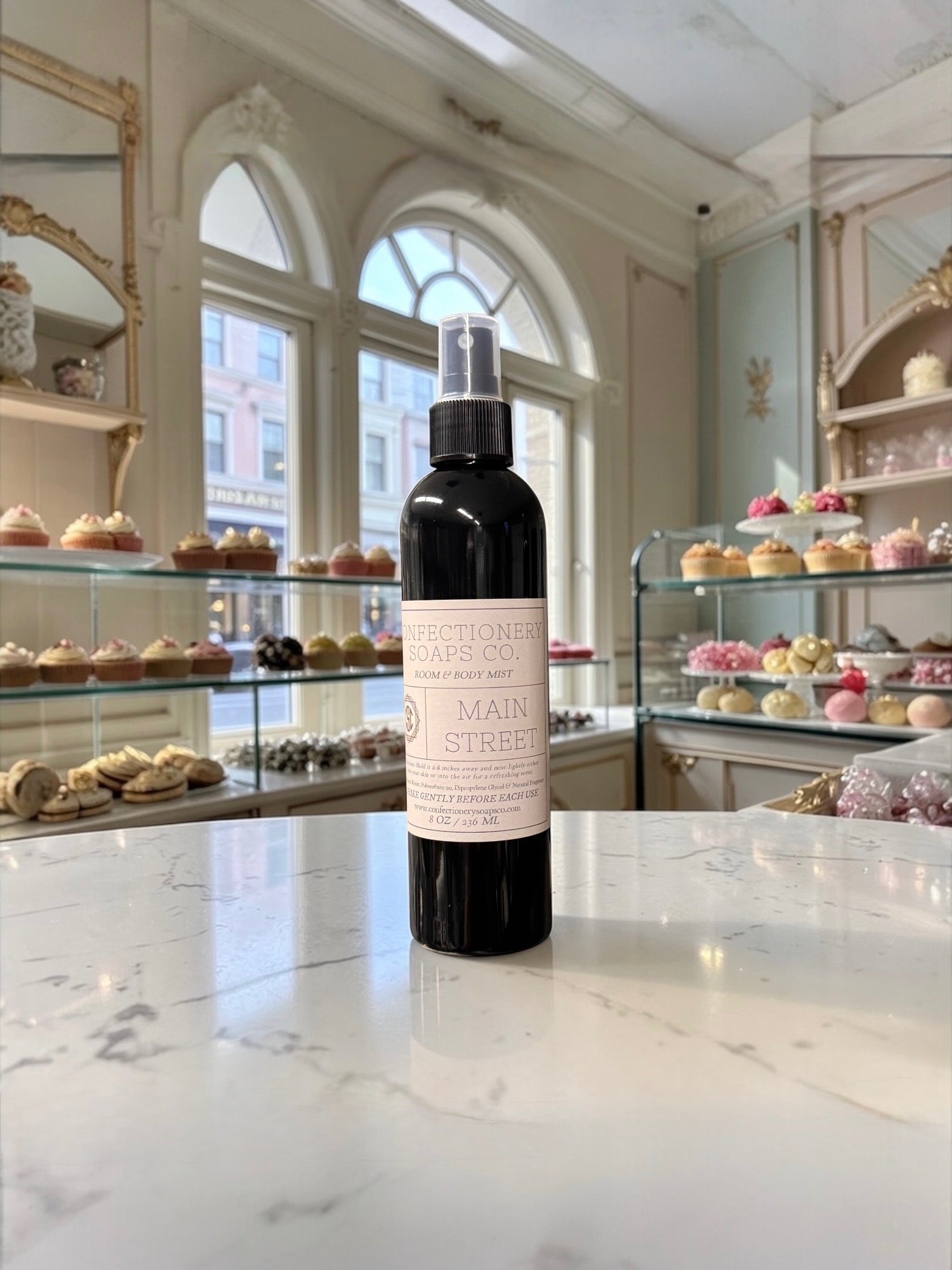 Black spray bottle with a label on a marble counter in a bakery.