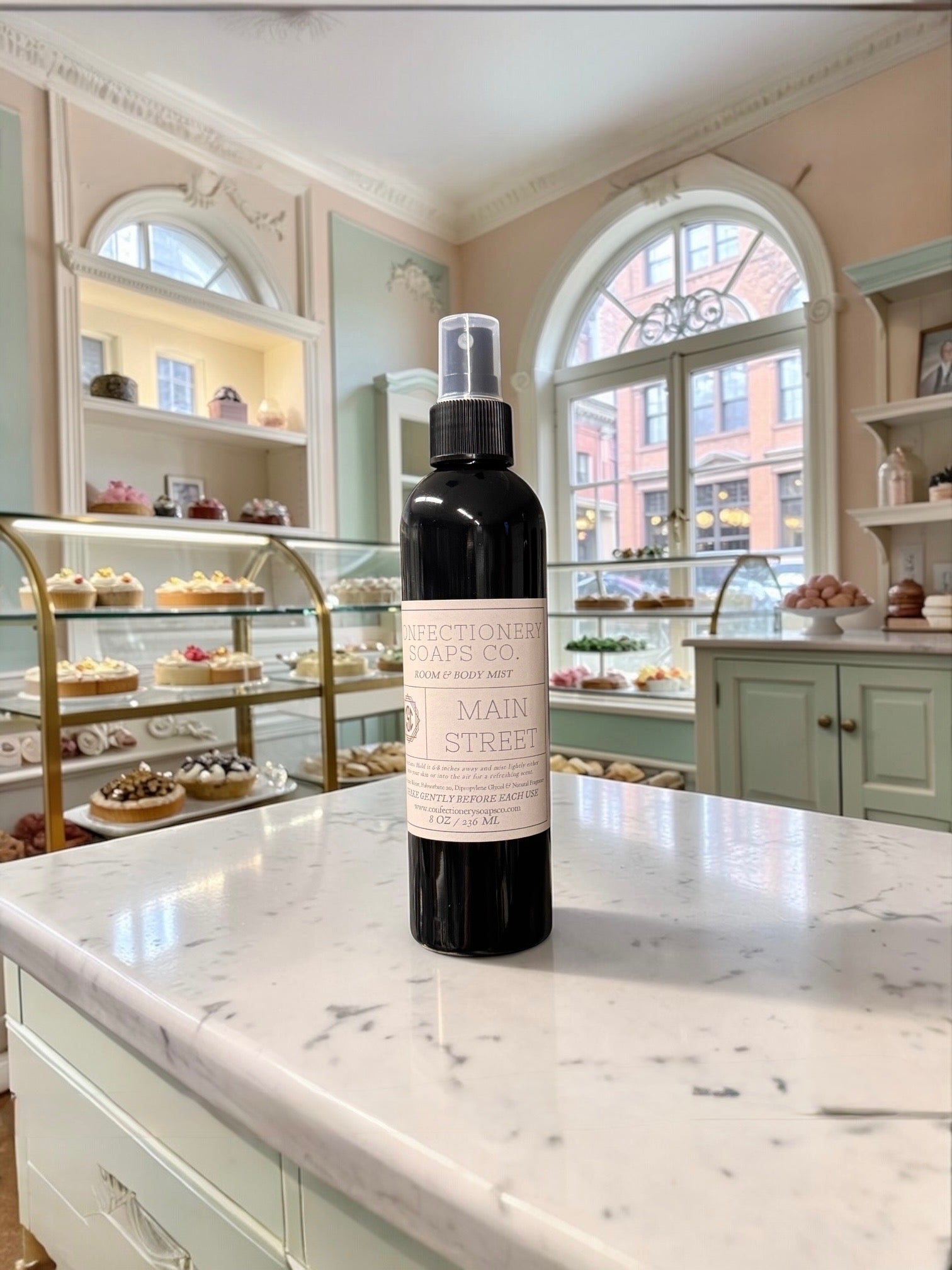 Black spray bottle with pink label on a marble countertop in a bakery setting