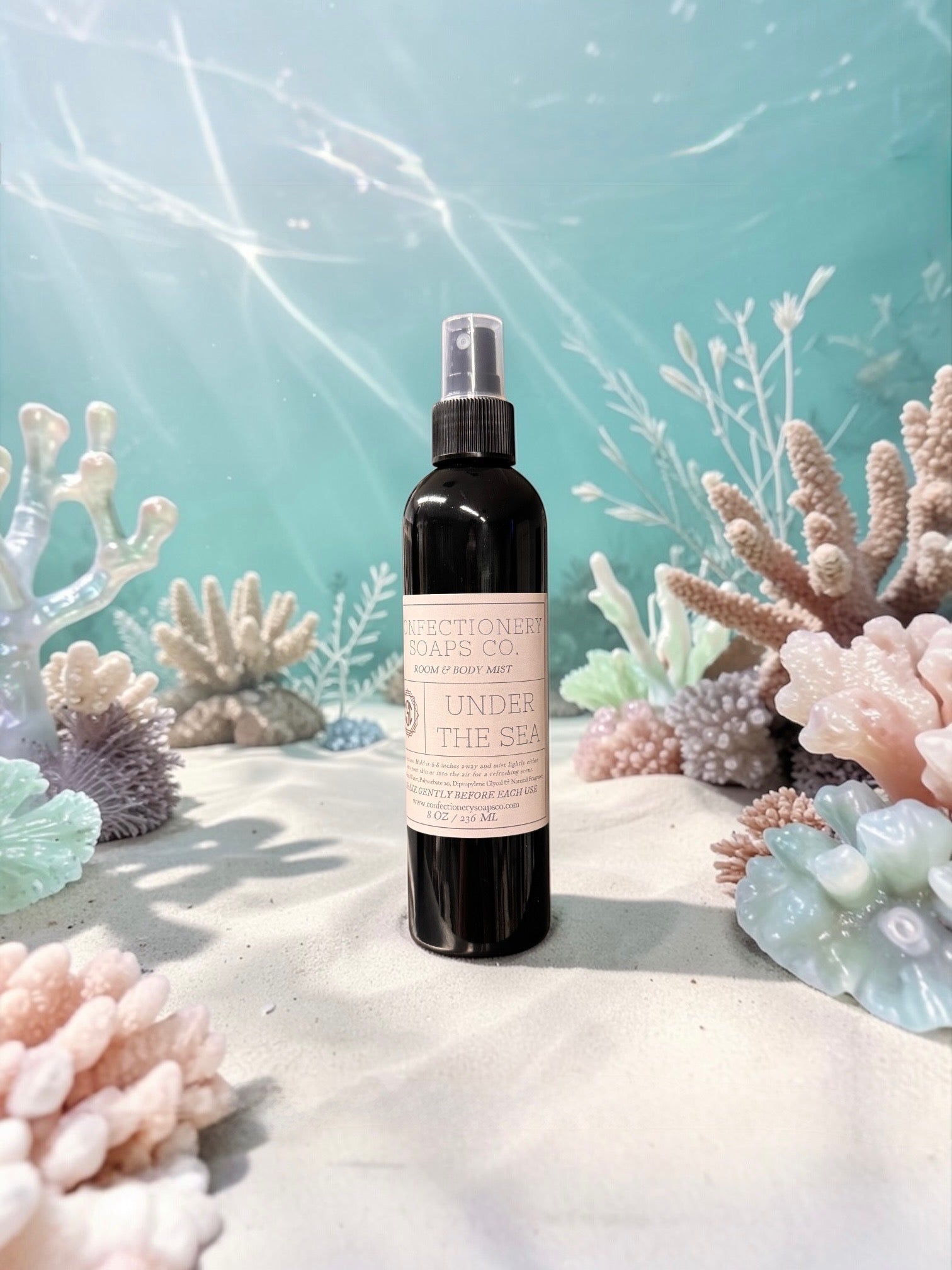 Black spray bottle with a label on a sandy surface with coral decorations