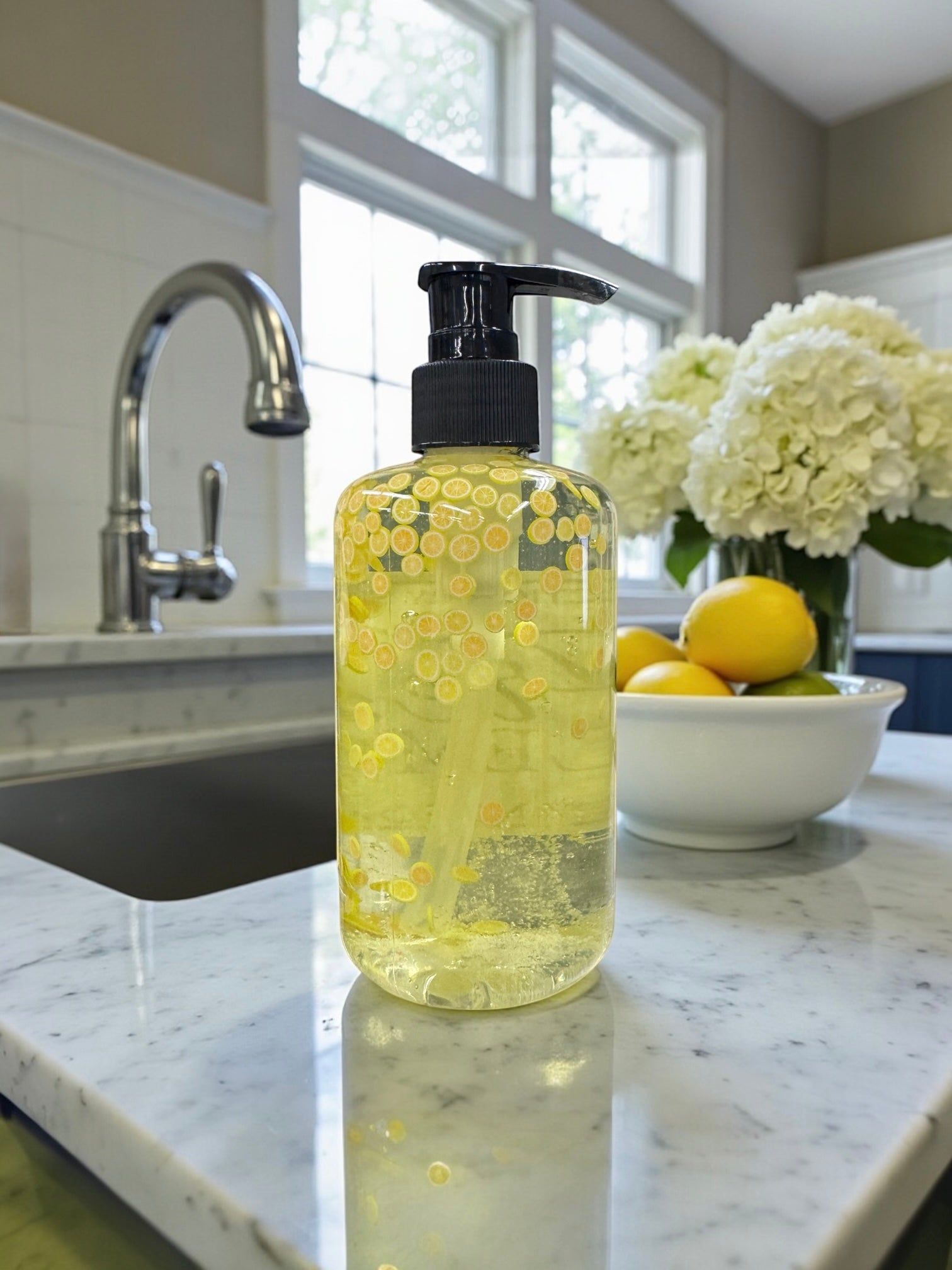 Bottle of yellow liquid soap on a kitchen counter with a window and sink in the background.