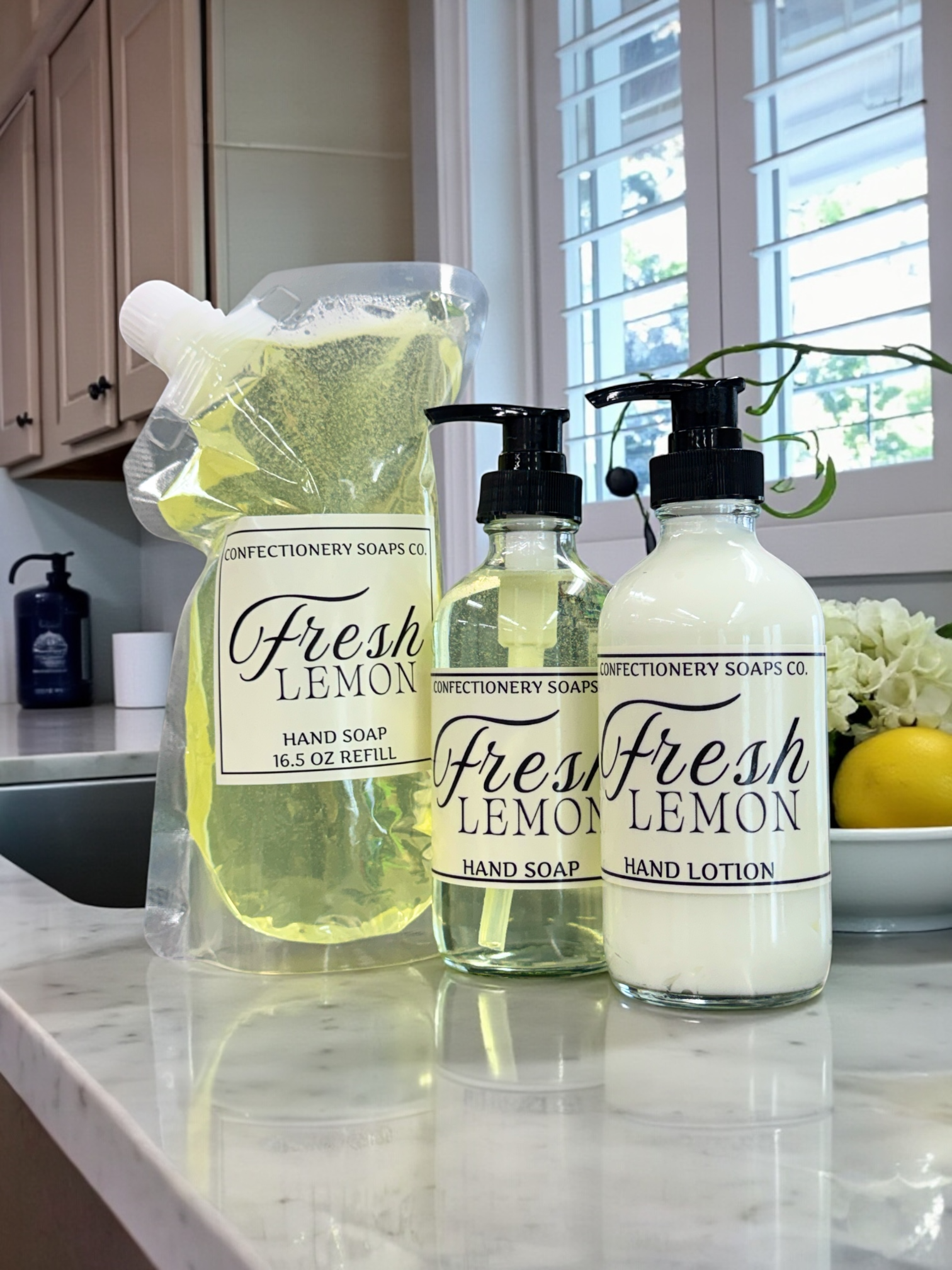 Set of Fresh Lemon hand soap, hand lotion, and refillable pouch on a kitchen counter.