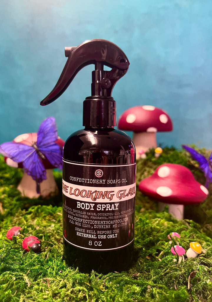 one body spray sitting on top of grass, whimiscal mushrooms , butterflies and lady bugs surrounding product. 
